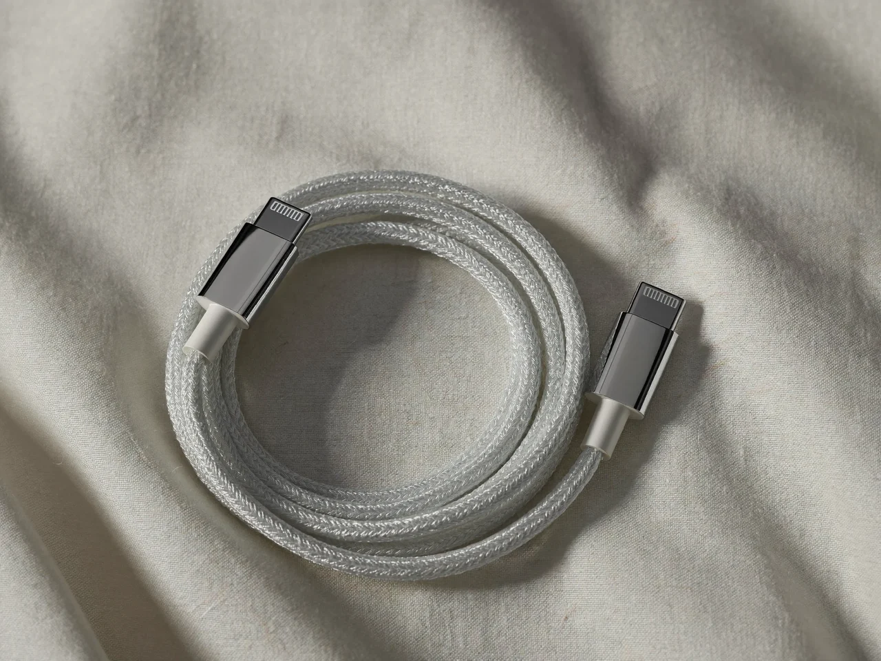 Oplatany kabel USB-C zwinięty na lnianej tkaninie, z metalowymi końcówkami