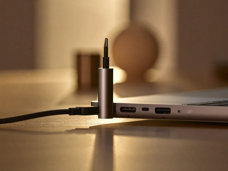 Smukły hub USB-C podłączony do krawędzi cienkiego laptopa na drewnianym biurku